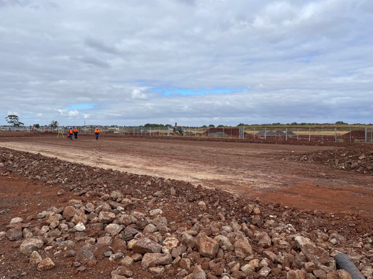 Aintree Secondary School (interim name) - construction photo of site progress in January 2023 - red dirt paddock with loose rocks in foreground