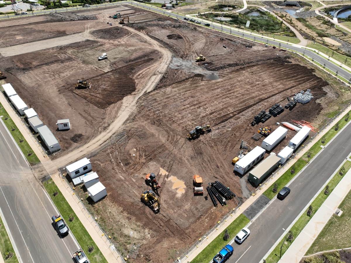 Black Forest East Primary School (interim name) - construction site progress in January 2023 - aerial shot of site showing flattened earth, dirt roads, portables and roads surrounding site. 