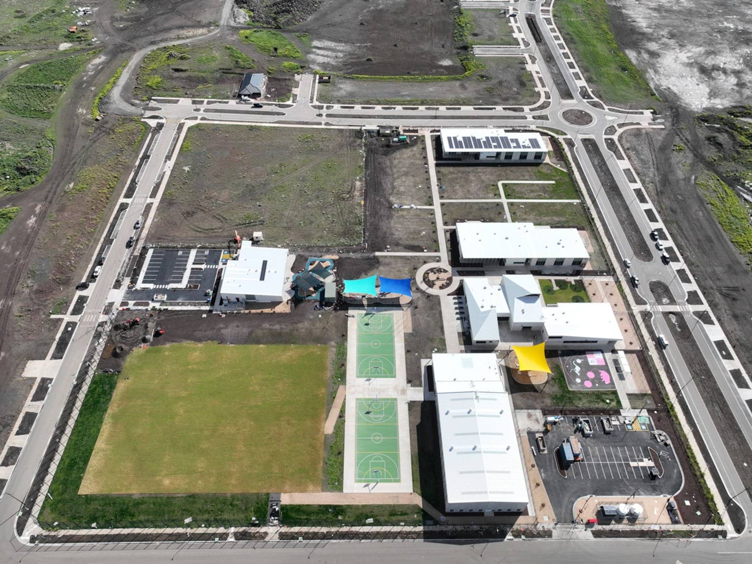 Aerial photo of school site with oval, basketball courts, and buildings in progress