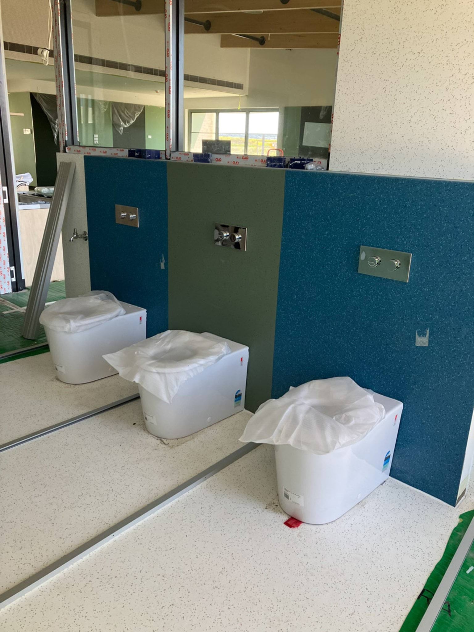 Kindergarten toilets plumbed in with plastic coverings still protecting them