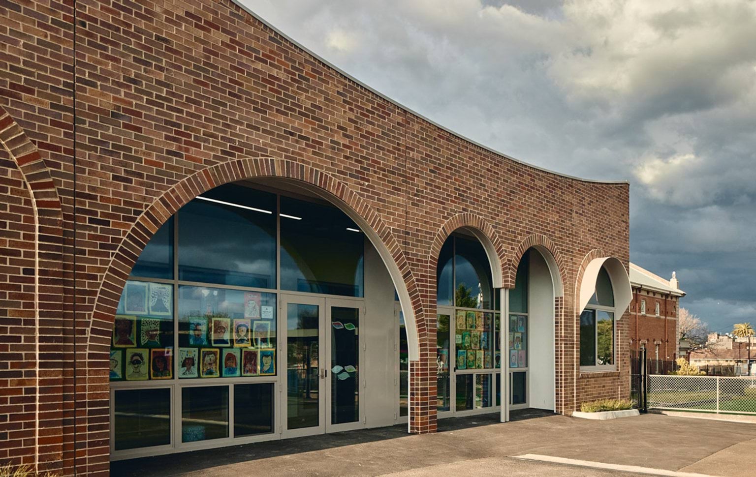 Outdoor photo of school entry. It is a brick building with curved arches above the doorway and windows.