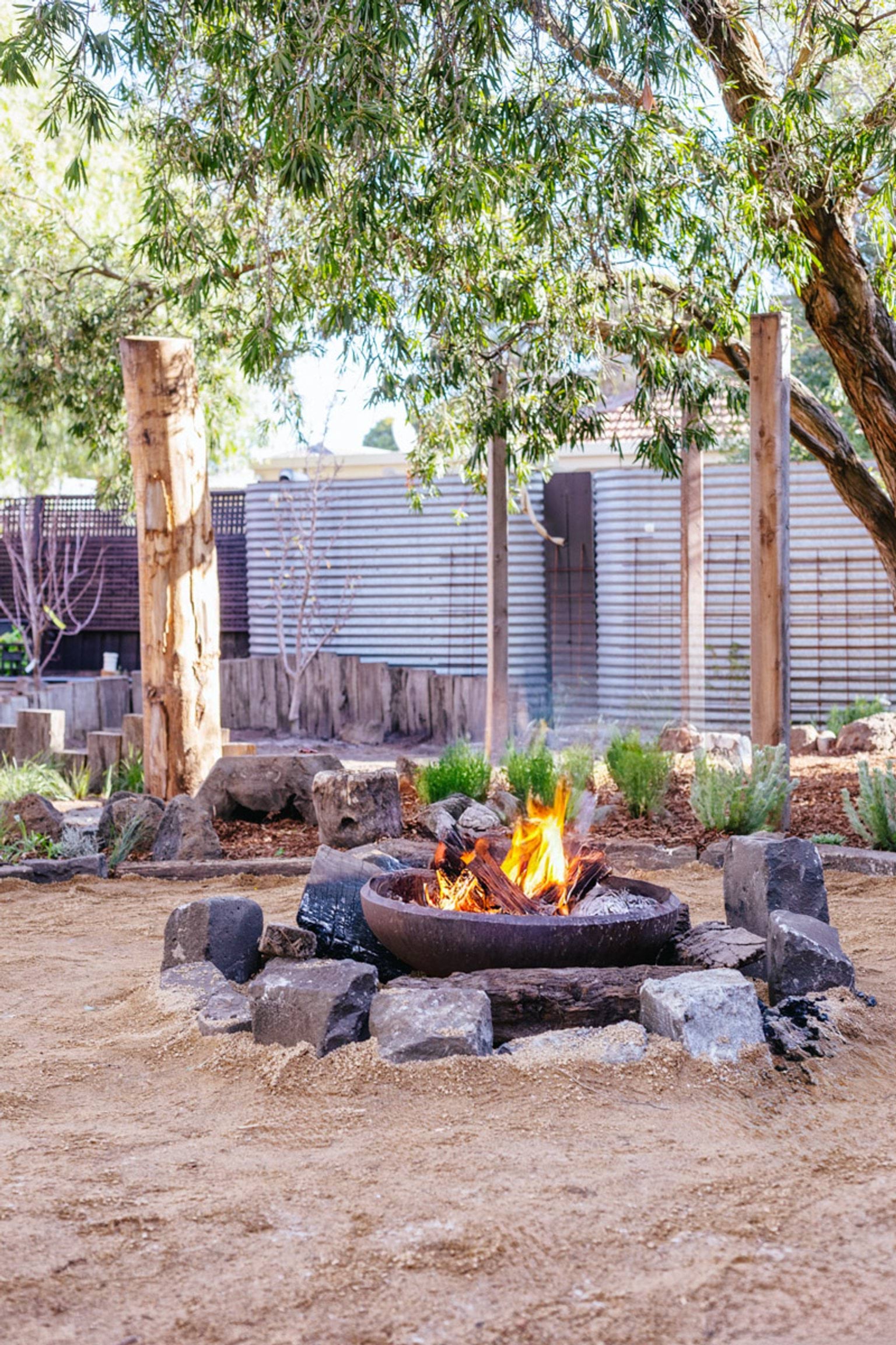 A fire pit outside with stones around it and trees in the background. 