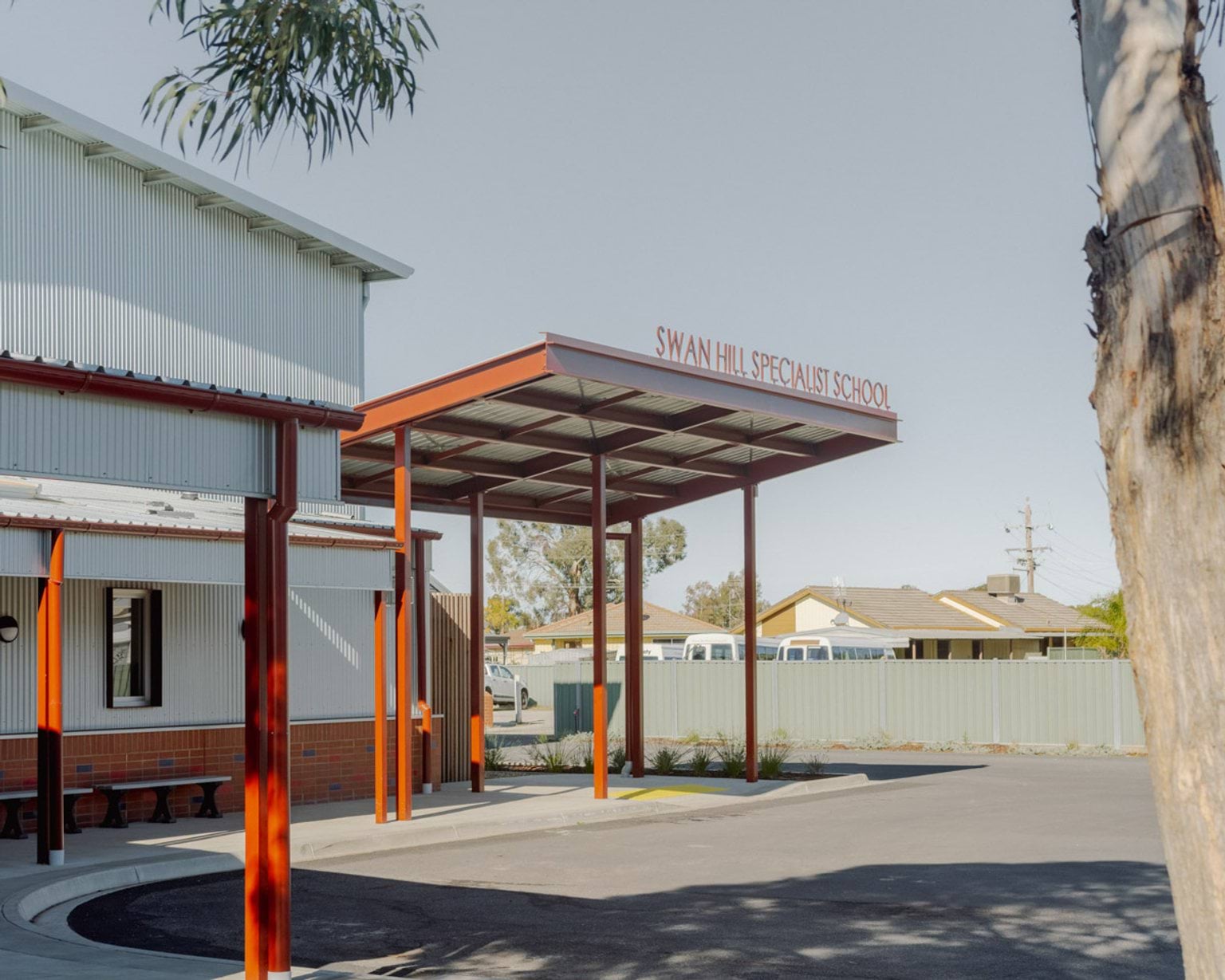 The outside of Swan Hill Specialist School. There is a covered roof area over a section of the road. The school's name is written in metal letters standing on top of the roof.