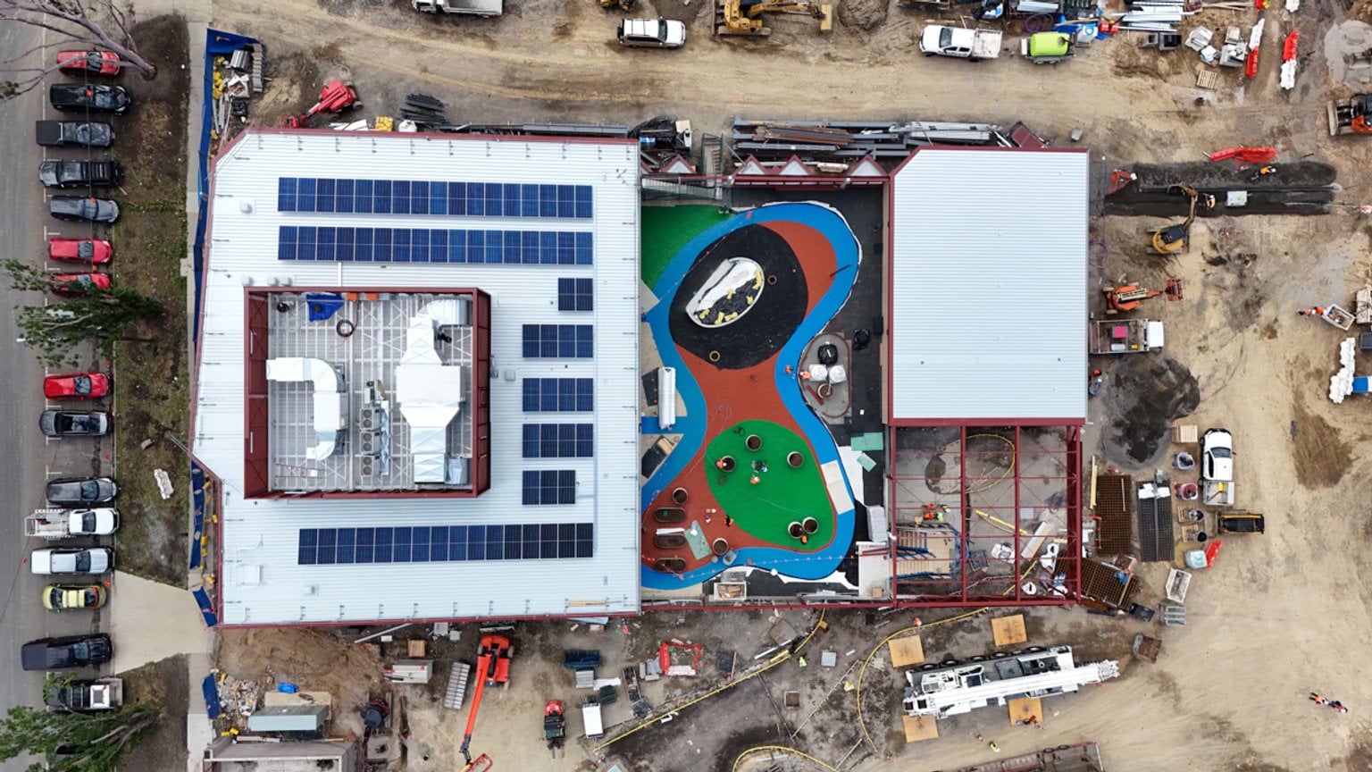 Aerial photograph looking down on Narrarrang Primary School displaying solar panels on main roof and brightly coloured playground.