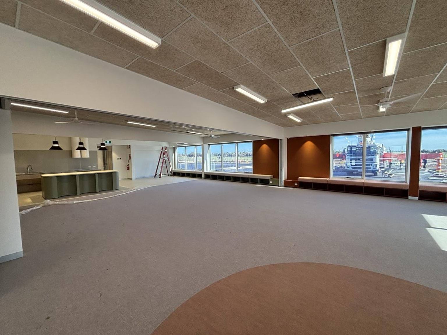 Inside one of the new buildings at Ngurraga School. There is carpet on the floor, brown coloured feature walls, and lighting switched on.