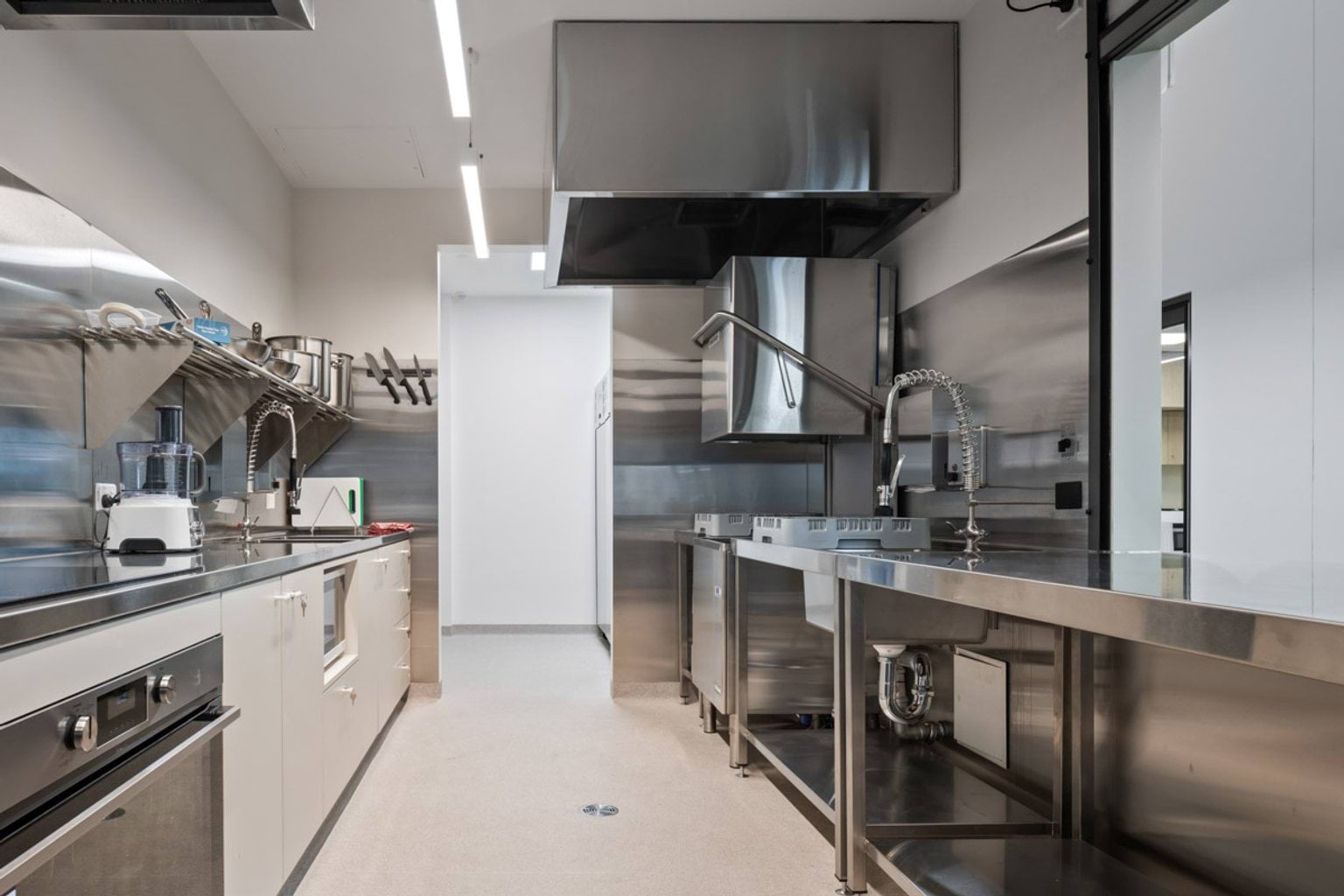 Kitchen with stainless steel benches, appliances and overhead exhaust canopy for food preparation