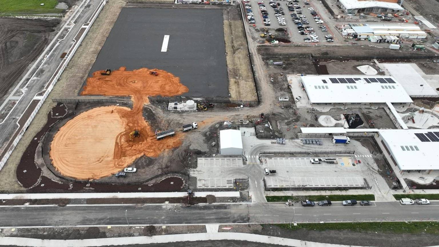Aerial photo of construction site where trucks are taking dirt away 
