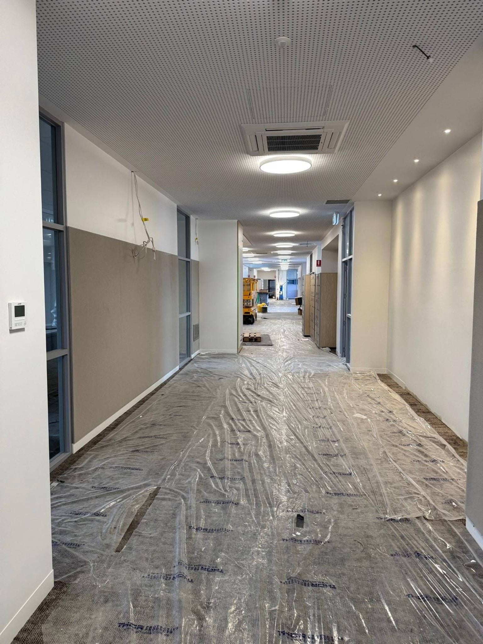 Hallway with dropsheet on floor and construction equipment in background