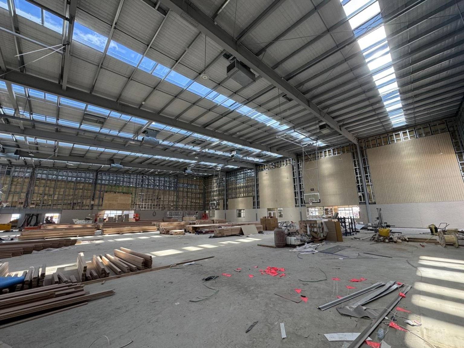 Indoor gym area with construction work happening under a high ceiling