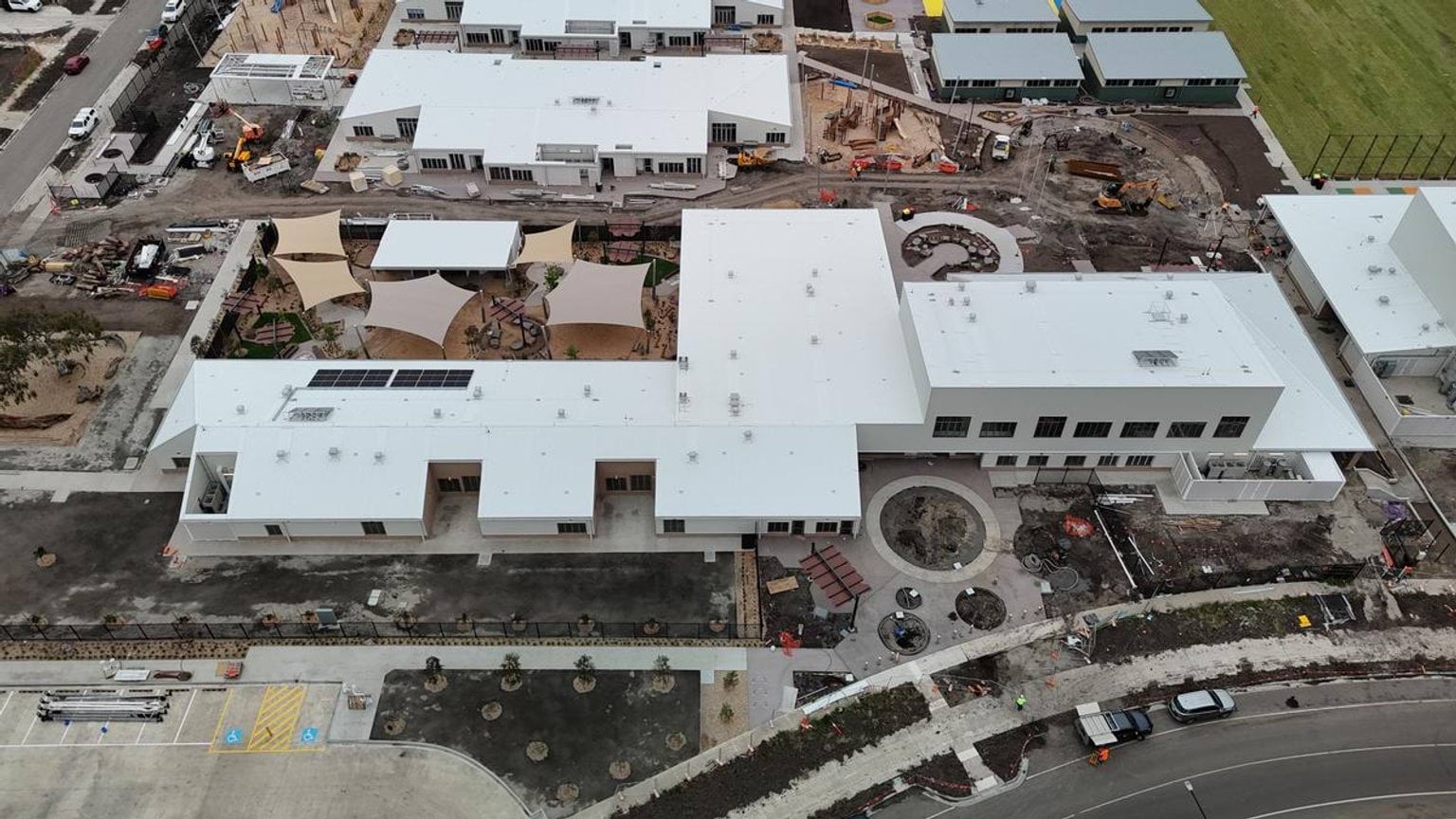 Aerial photo of school under construction. There are multiple buildings, an undercover outdoor area, and a road outside.