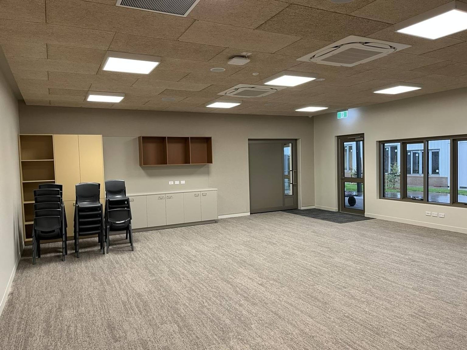 Indoor school room with cupboards, shelves, and stacked chairs at the back of the room