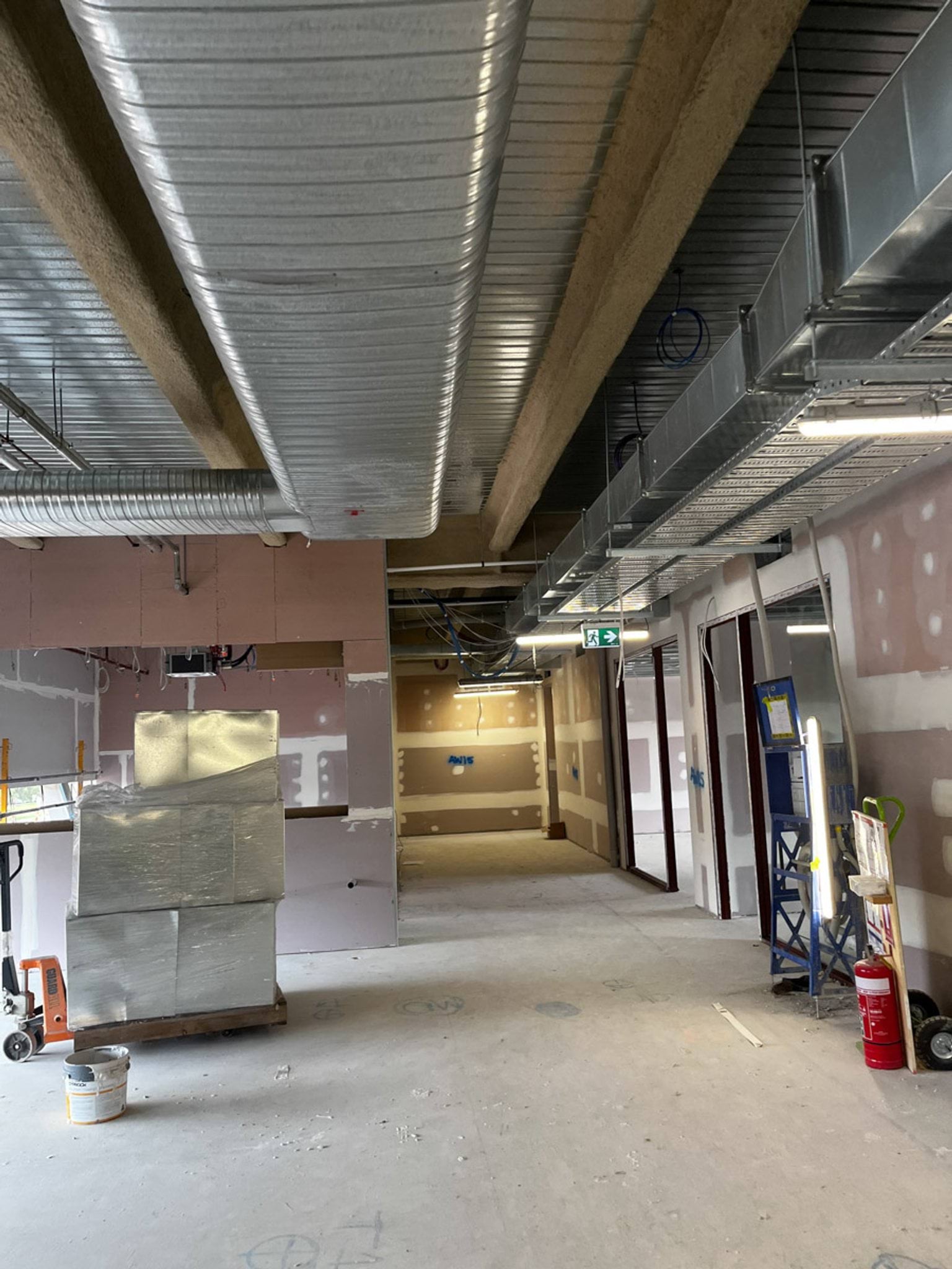 Hallway under construction. Air vents and construction equipment are visible.