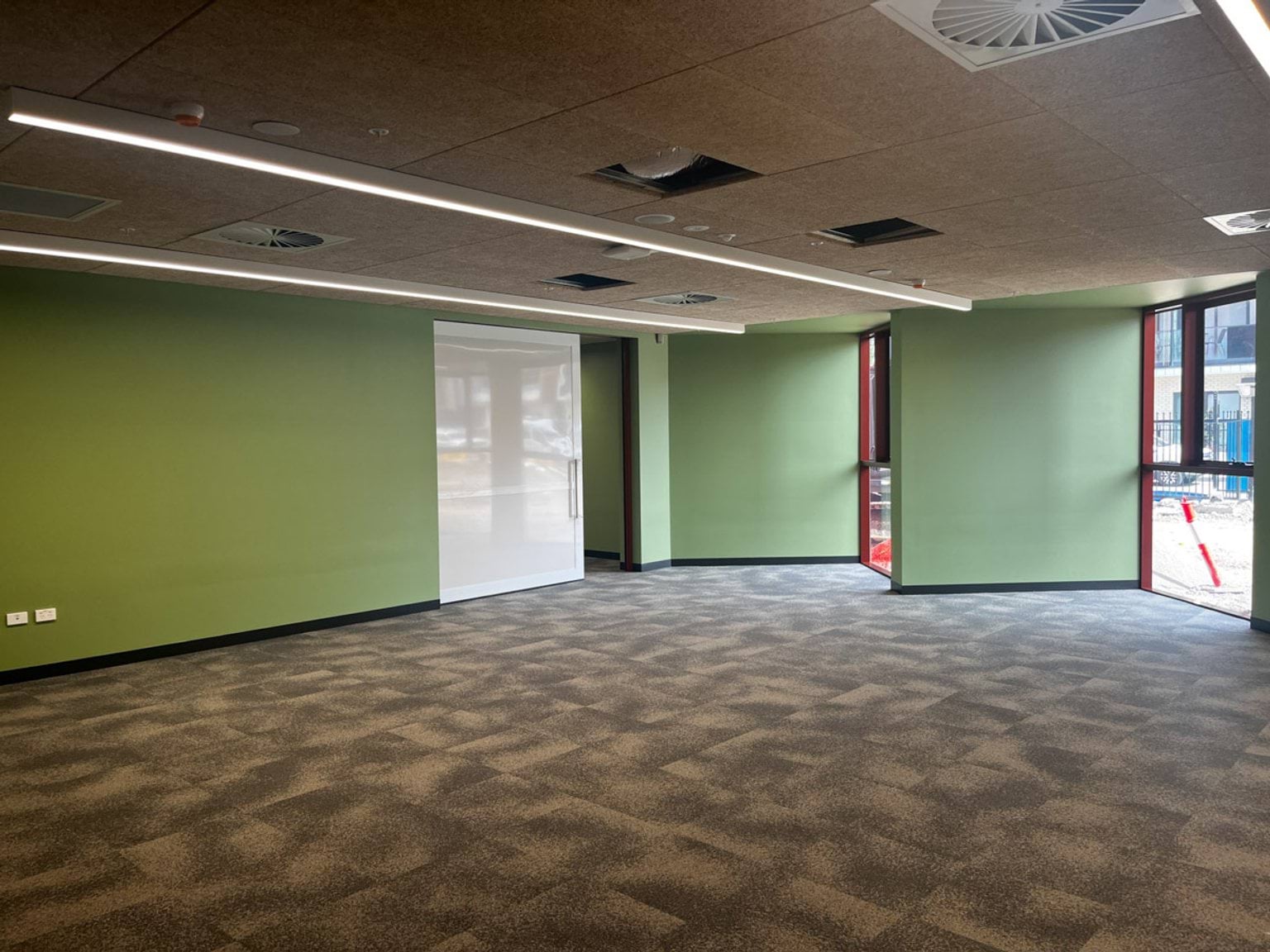 Classroom under construction. There are green walls and large windows facing outside