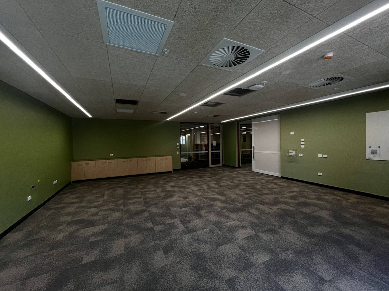 Classroom with green walks, cupboards at the back, and overhead vents