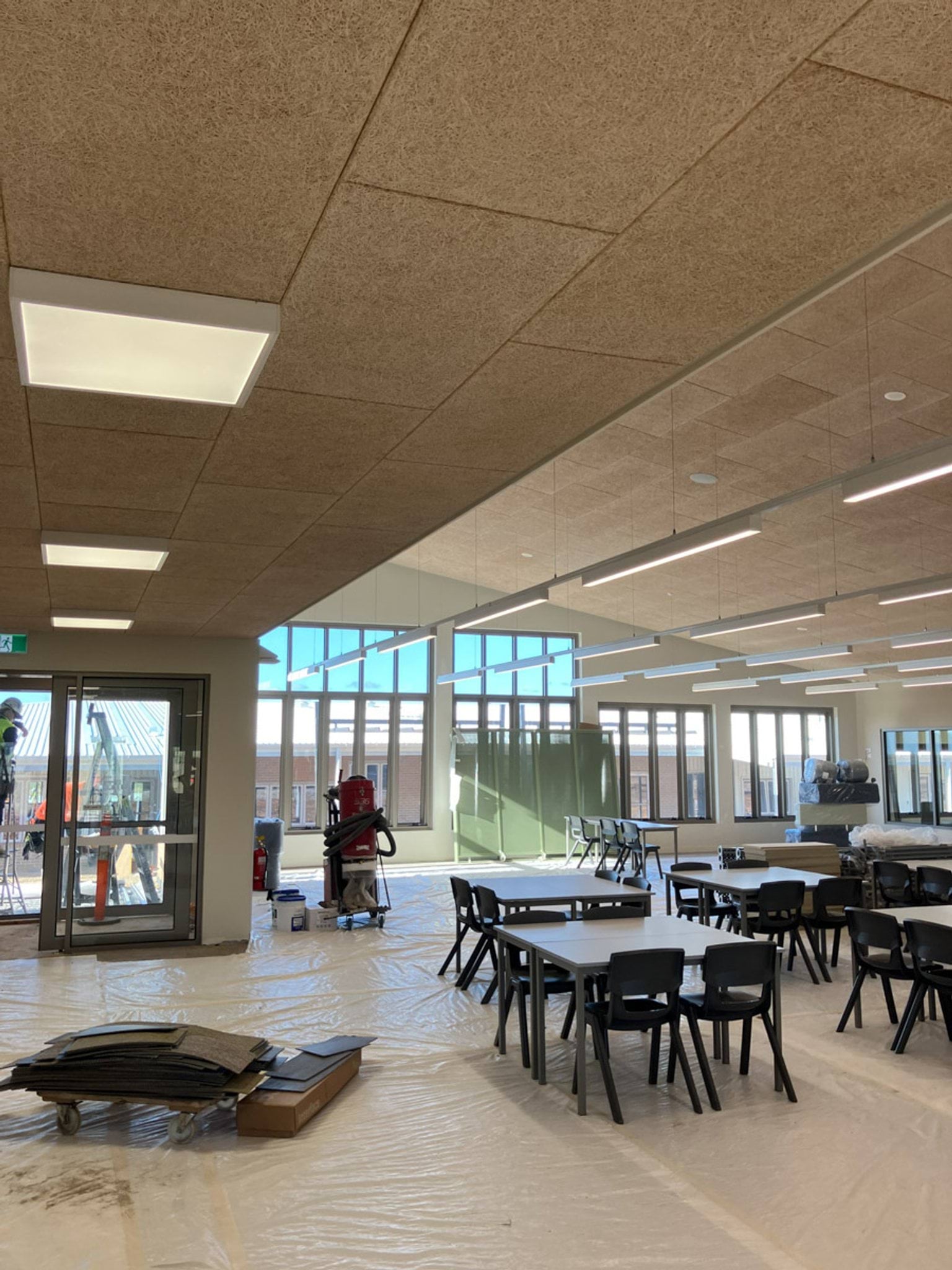 School room with chairs at tables, large windows, and drop sheets on floor