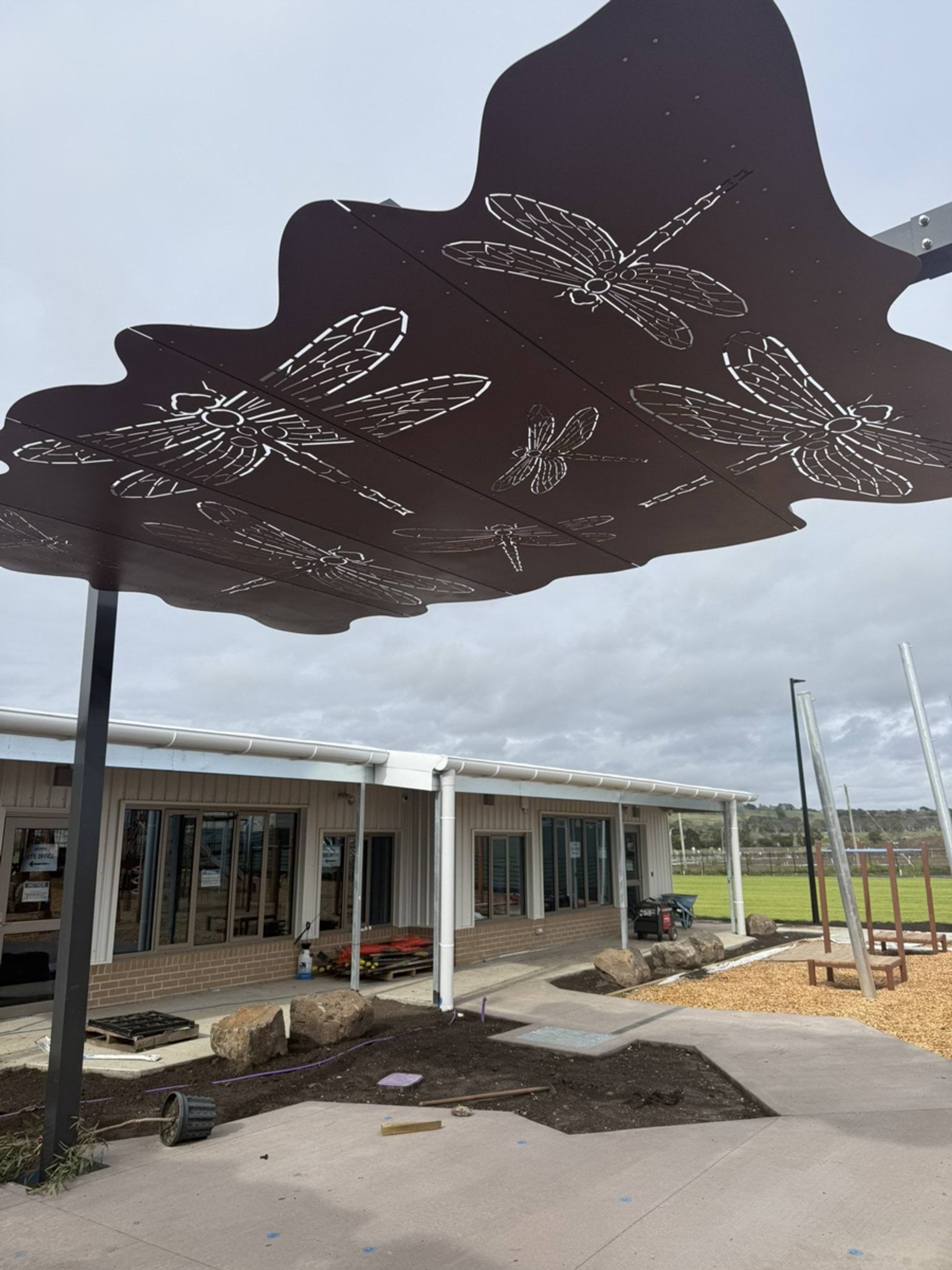 Outside Gamadji Primary School, looking up at a shade sail with cut-out designs of dragonflies.