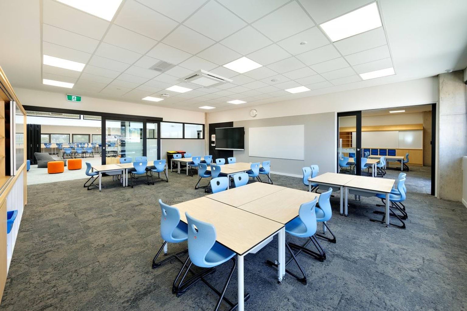 Inside a new classroom at Kerribana Primary School. There are groups of tables in the room with blue plastic chairs at them.