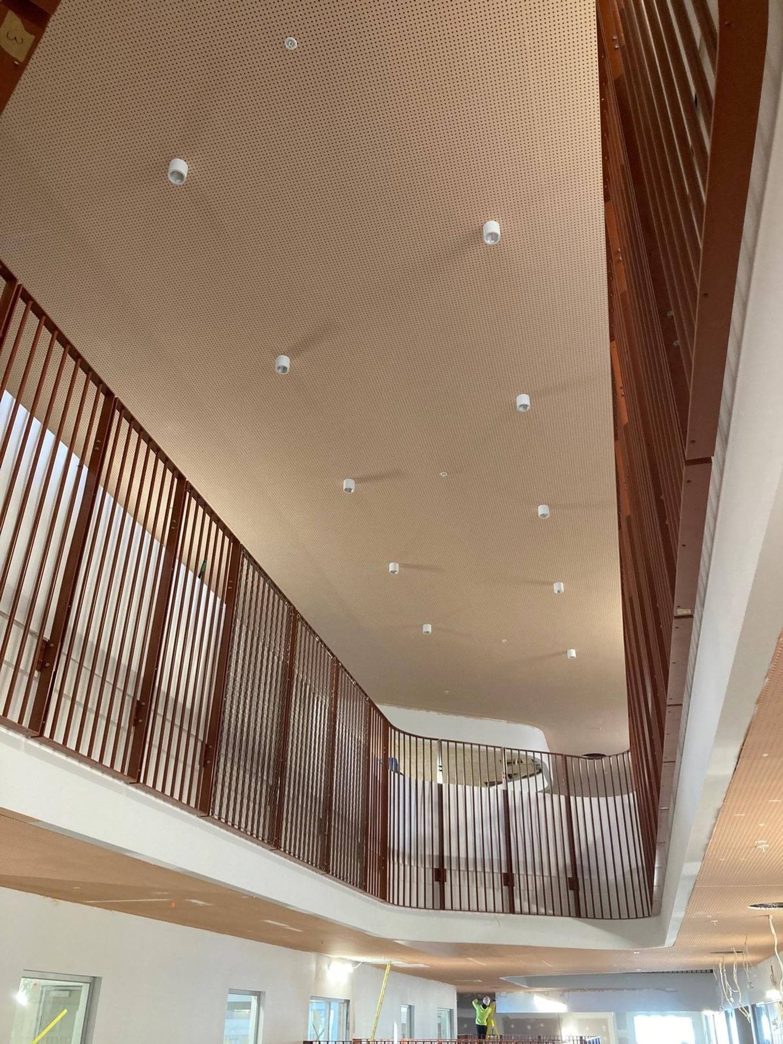 Completed railings on second floor of school building, looking down towards first floor.