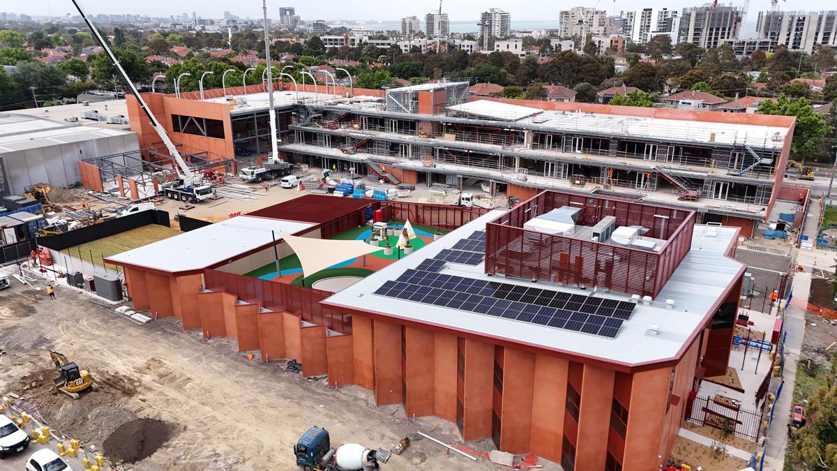 A wide overhead view of the kindergarten and surrounding construction, showing multiple buildings and outdoor play spaces.