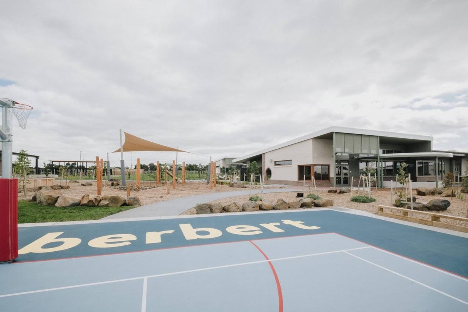 Outdoor sports court beside a landscaped play area and modern school building