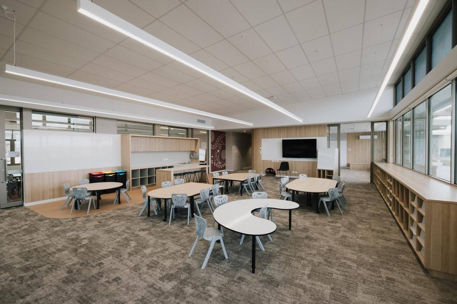 Flexible classroom with round tables, timber joinery and large windows for natural light