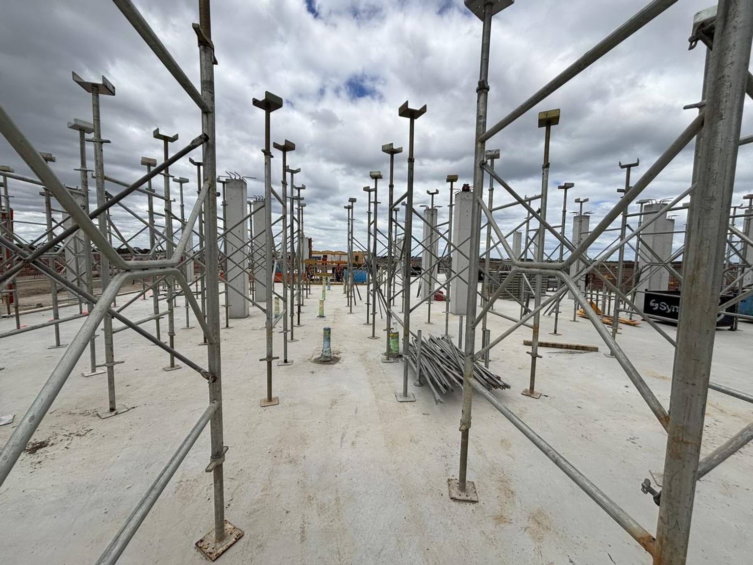 Concrete slab with metal scaffolding and support props arranged for upper-level construction