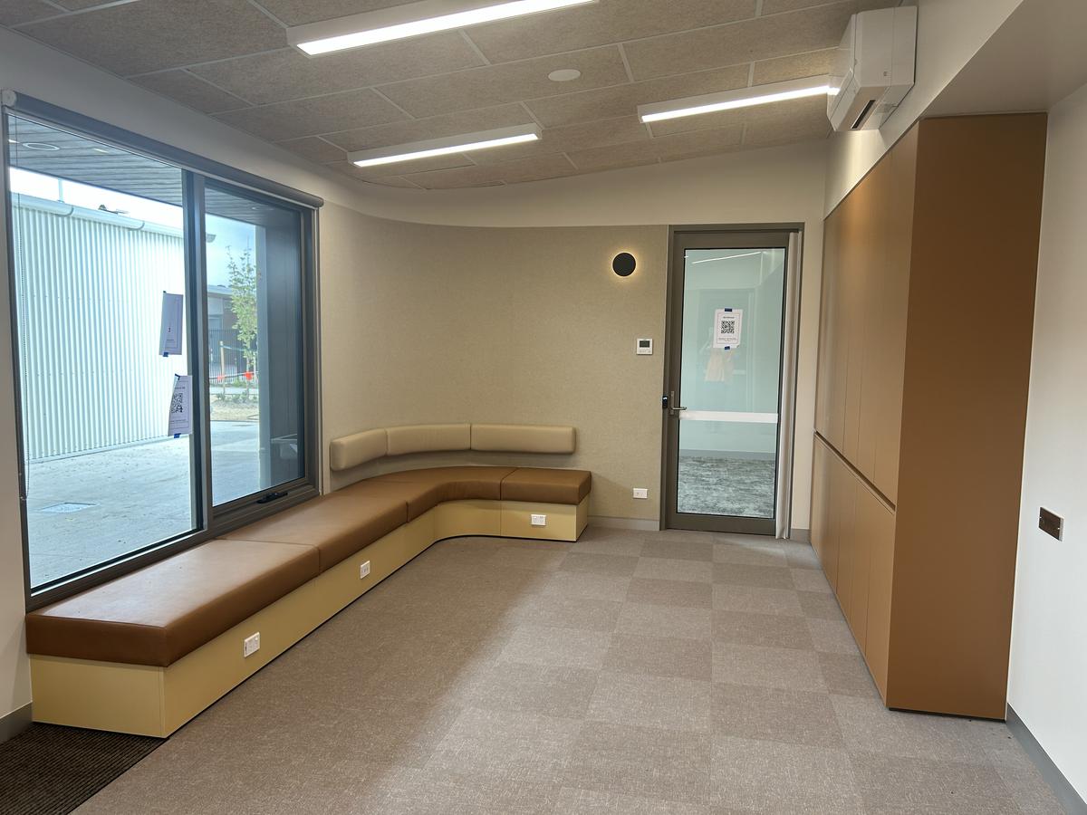 A breakout area with a long cushioned bench along curved walls, large windows, and built-in storage cabinets.