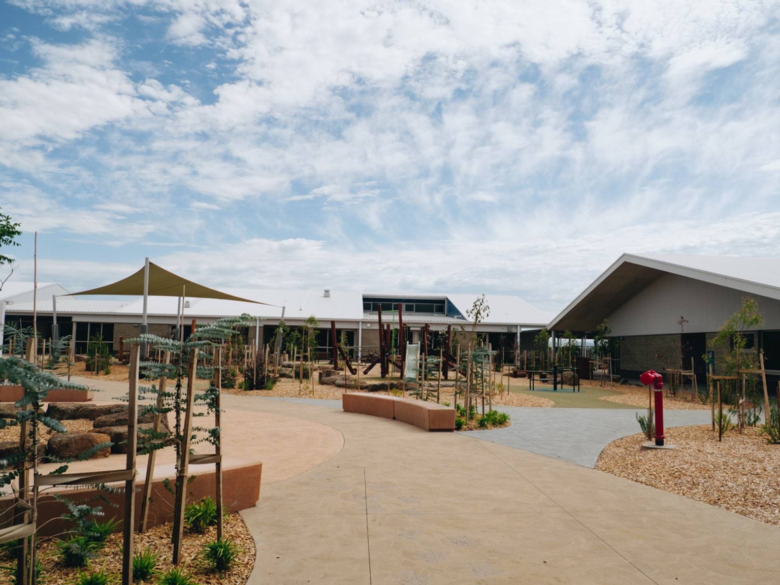 Central school courtyard with concrete pathways, shade structures and low-rise classroom buildings