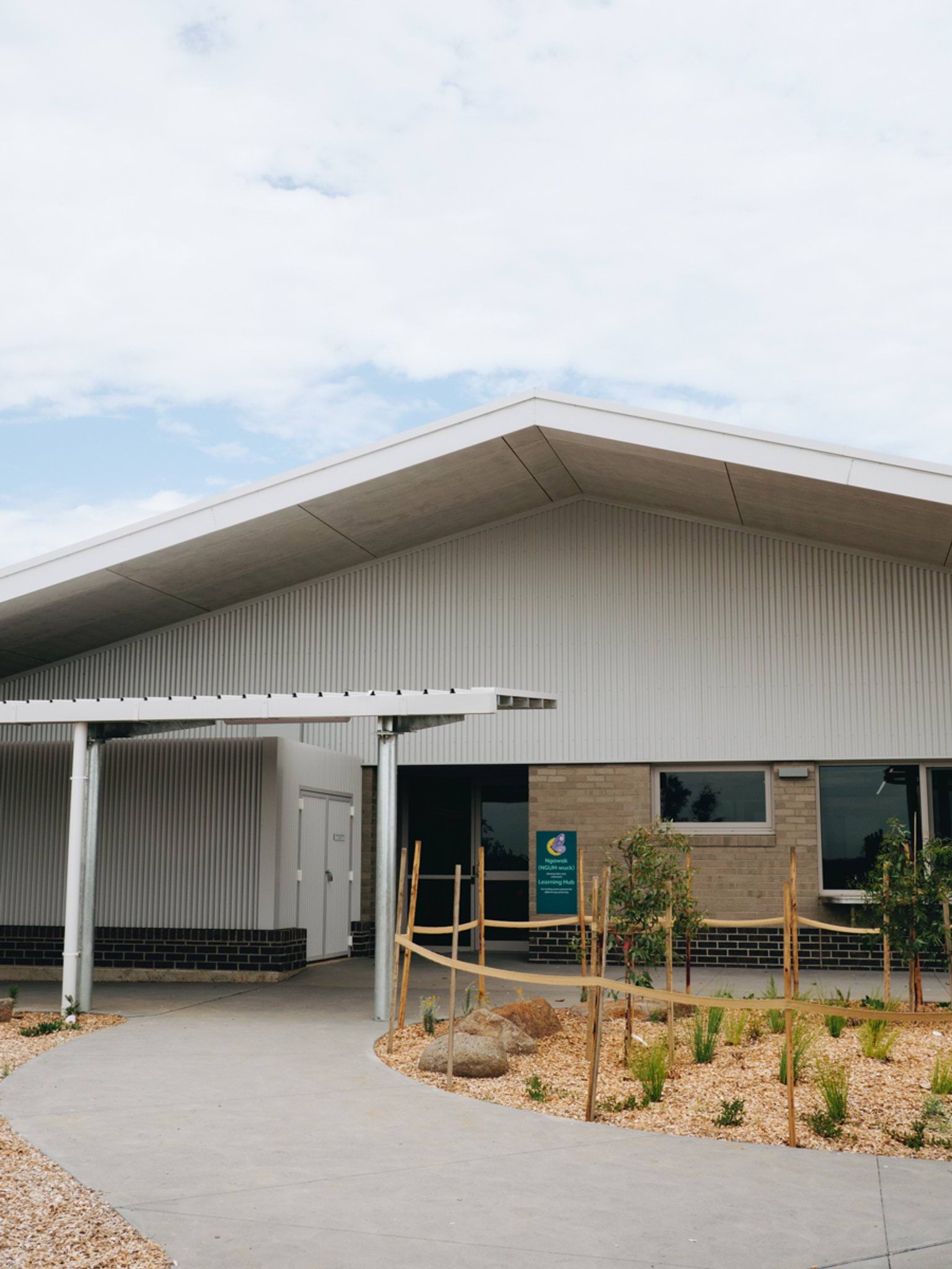 School building with pitched metal roof, covered entry walkway and brick and metal cladding