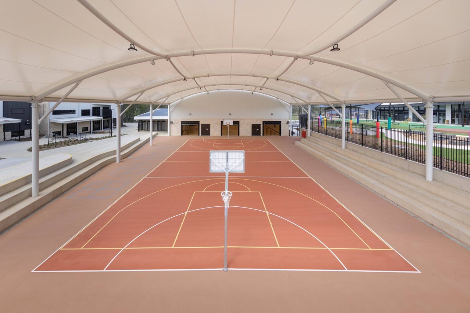 Covered outdoor sports court, marked playing surface and tiered concrete seating.