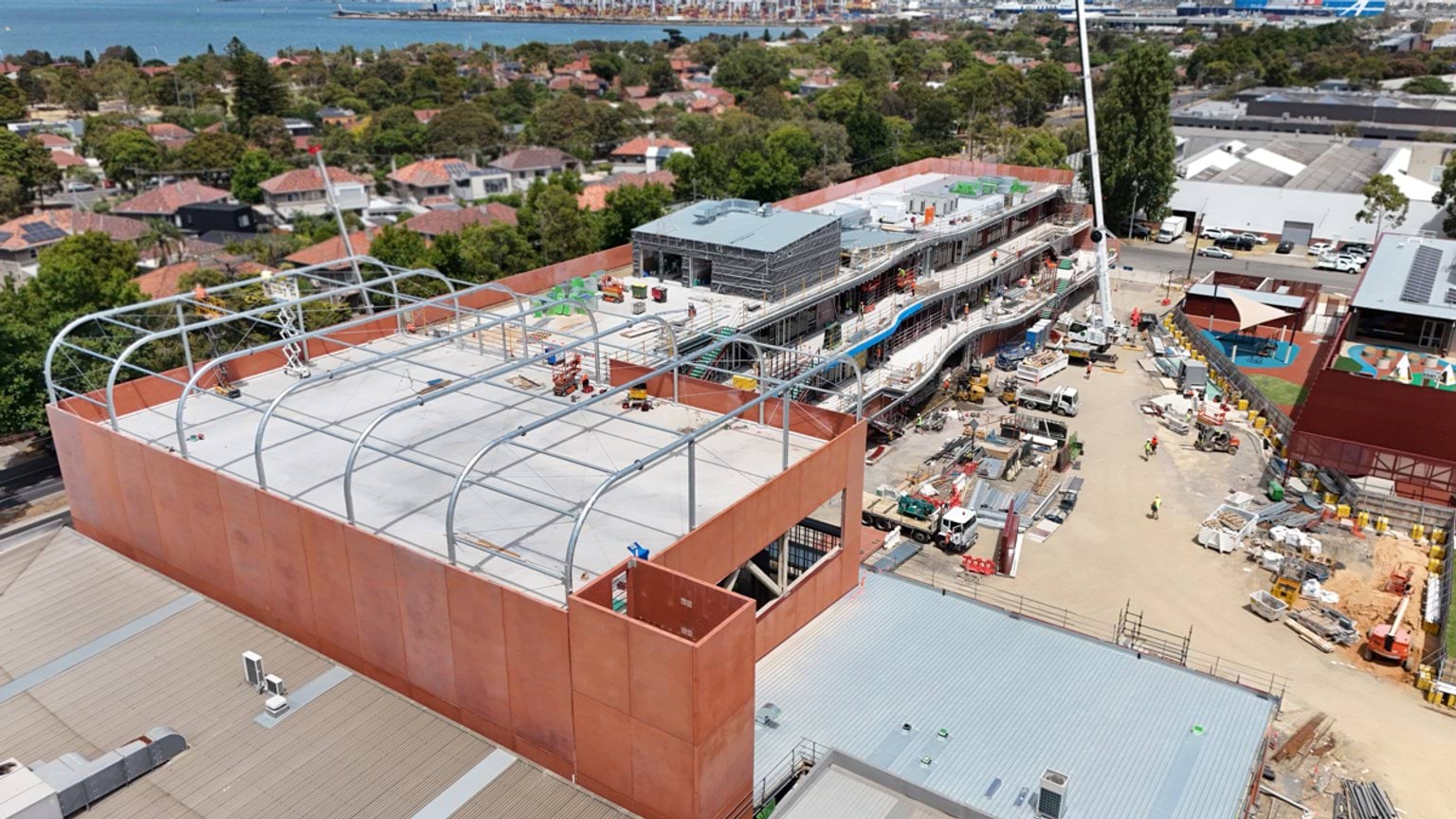 Aerial view of building structure with steel roof framing and adjoining classroom block under construction