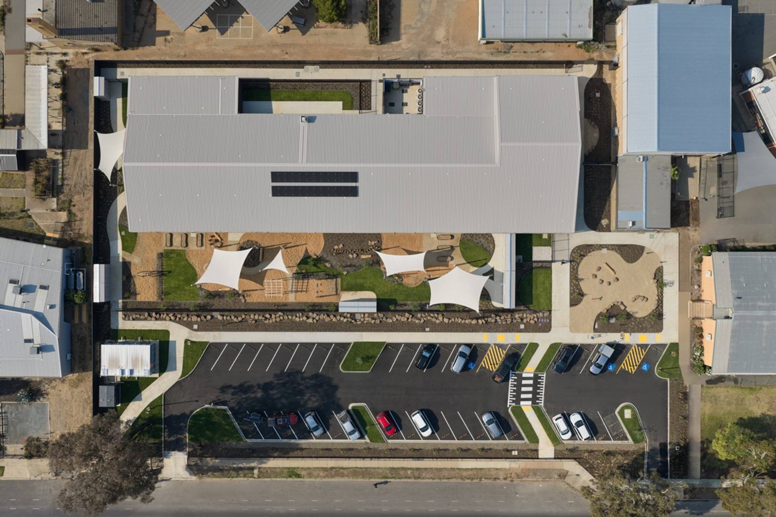 A top‑down aerial view of the early learning centre, showing the main building, outdoor play areas, landscaped gardens, and car park.