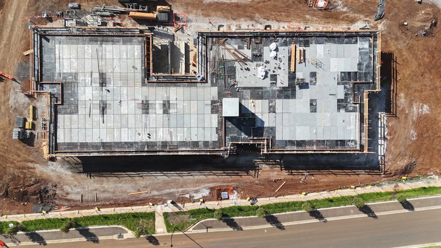 Top-down aerial view of a completed concrete slab forming the footprint of a school building, bordered by access roads
