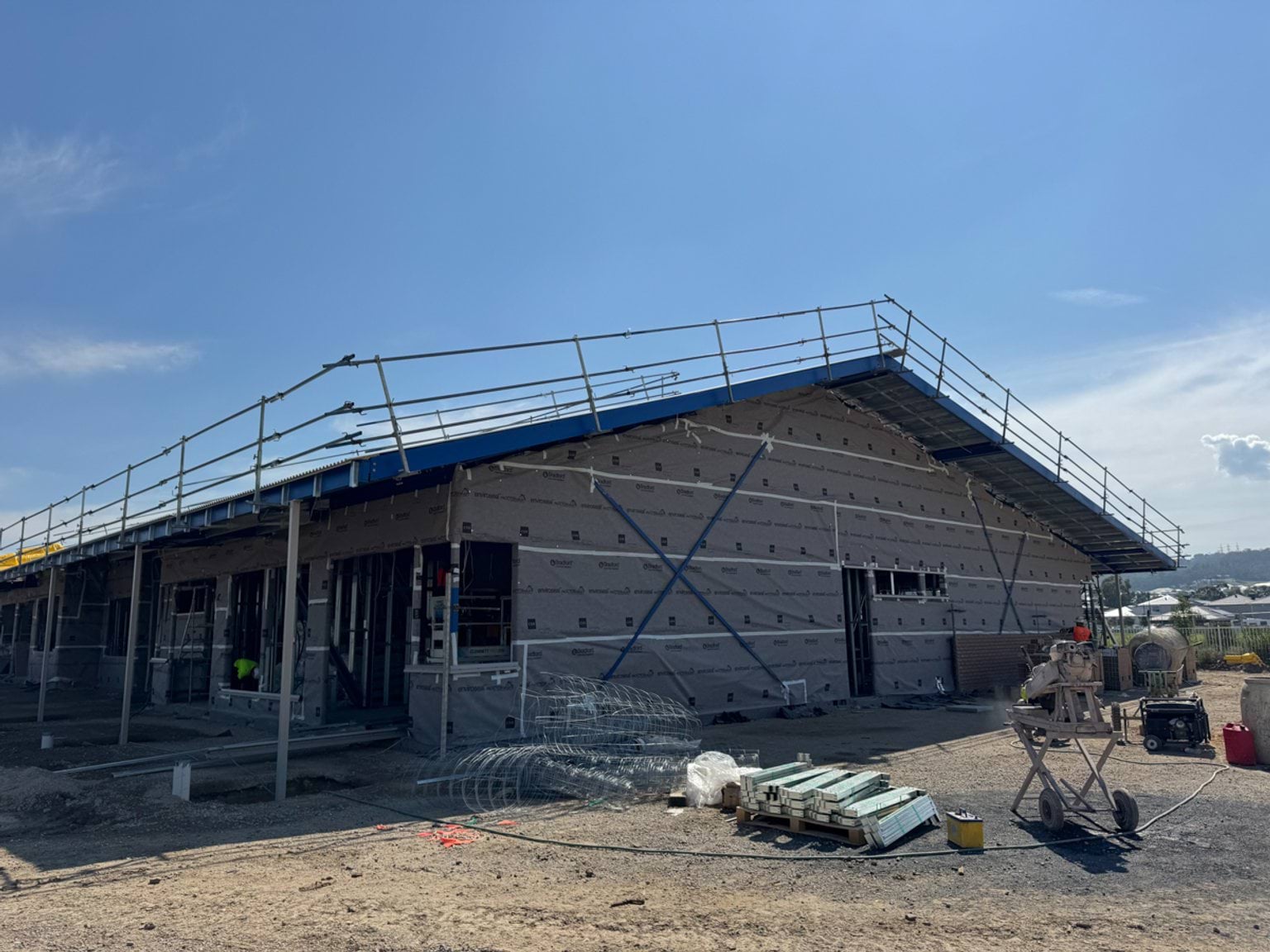 A single‑storey school building under construction with scaffolding installed and weatherproof wrap fixed to the exterior walls.
