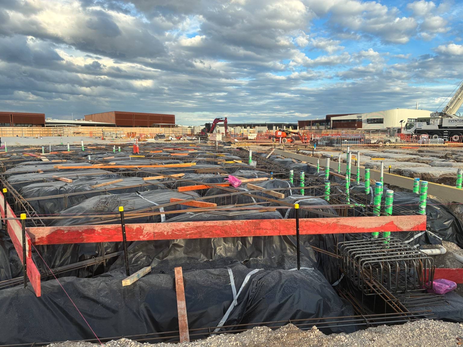 School construction site showing foundation trenches, waterproofing and steel reinforcement ready for concrete pouring