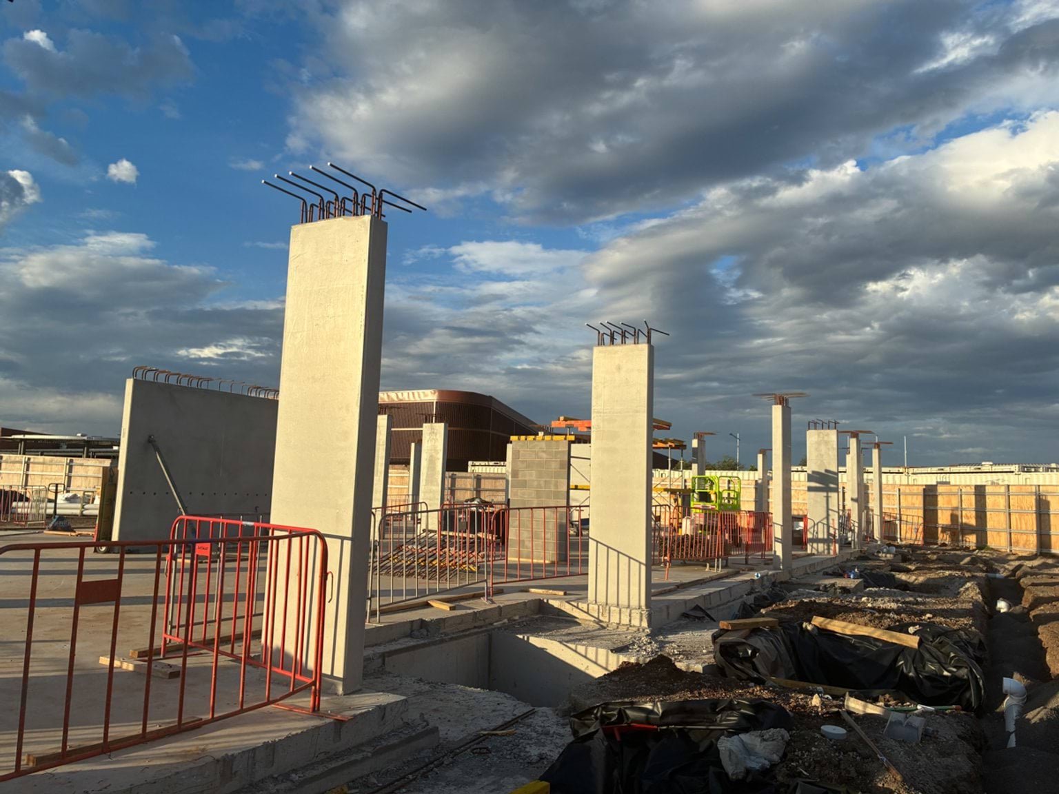 Concrete columns and footings under construction at a school site, with reinforcement bars extending above columns.