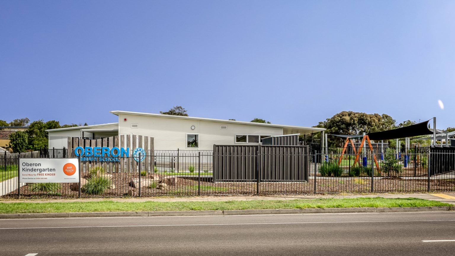 Street‑facing view of Oberon Kindergarten with fencing, playground equipment and building visible behind signage.