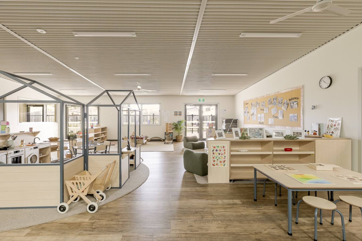 Wide view of an early years classroom featuring learning zones, low tables, storage units and play areas.