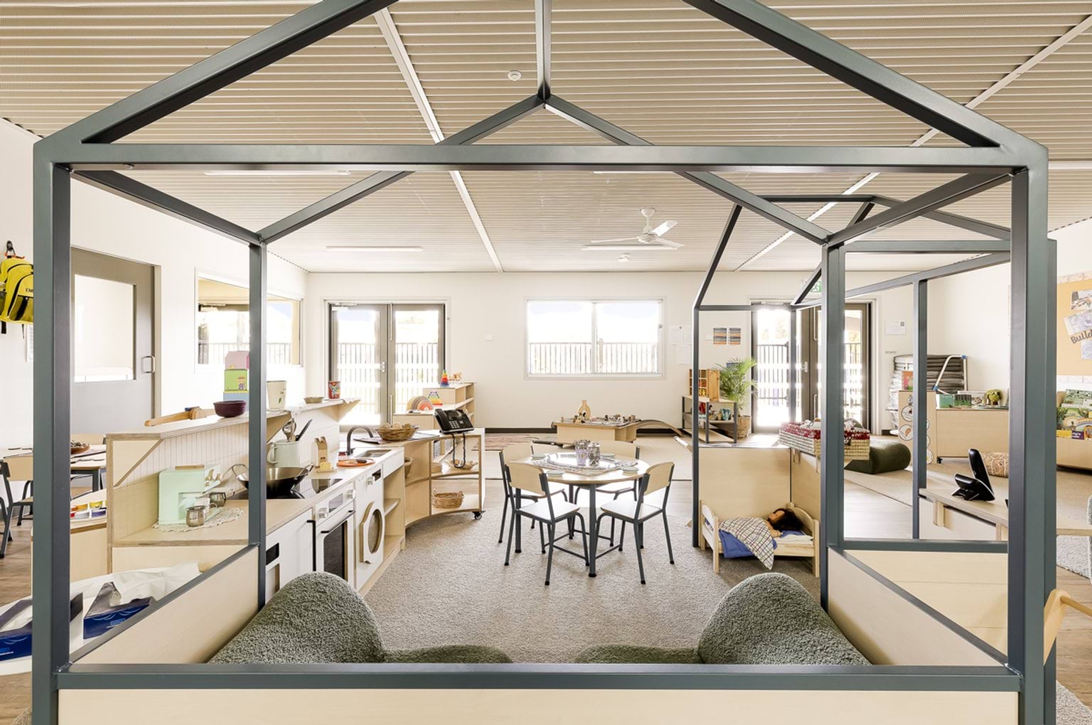 Play‑based learning area with a house‑frame structure, table seating and role‑play resources.