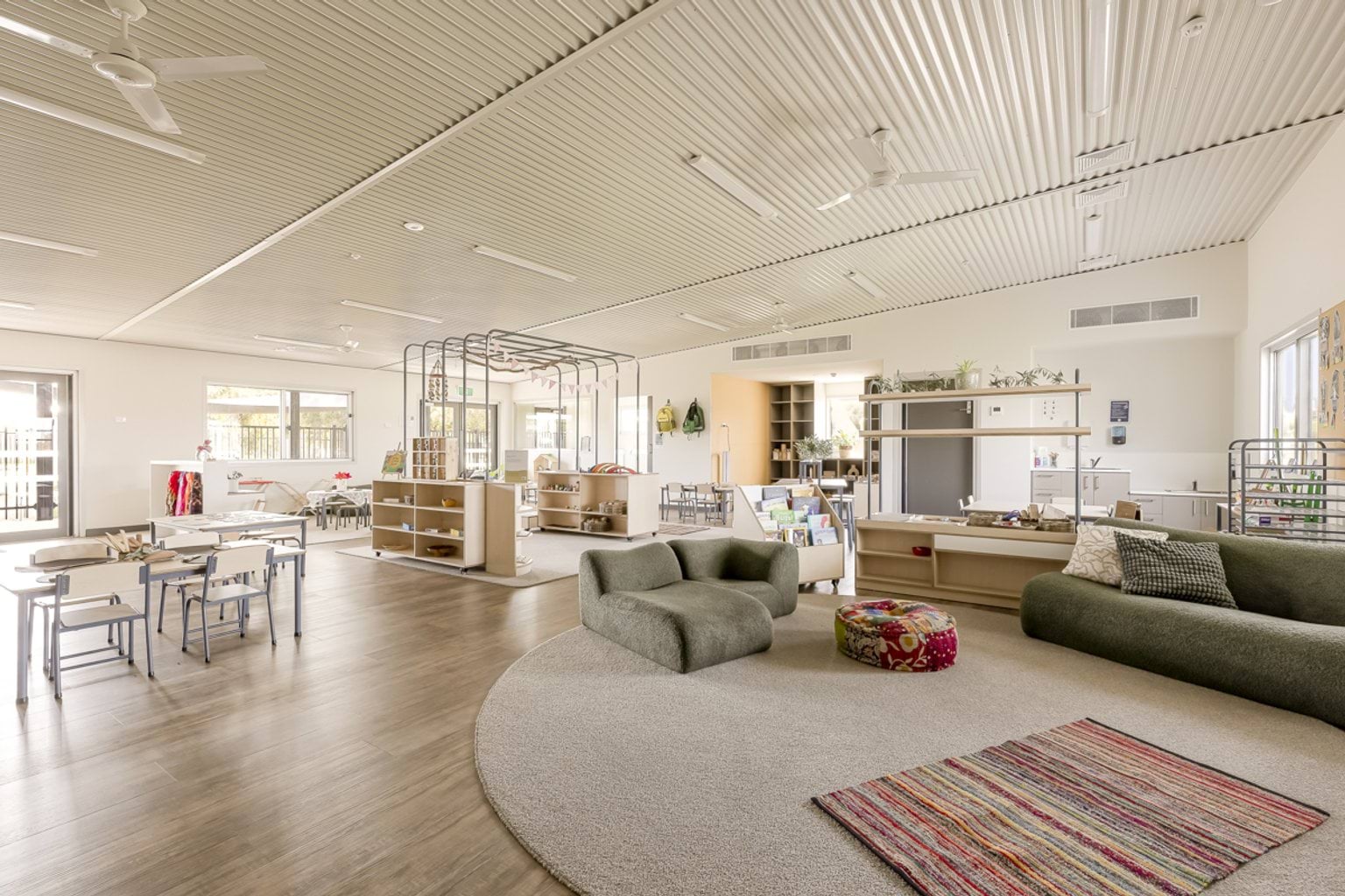 Spacious classroom with soft seating, learning stations, open shelving and natural light.