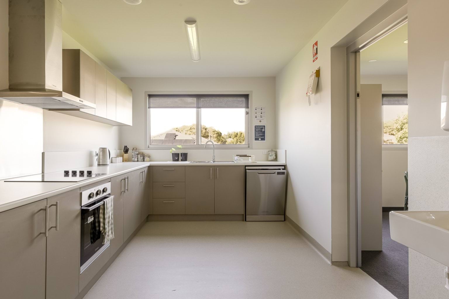 Staff kitchenette with cabinets, oven, sink and dishwasher adjacent to a staff amenities area.