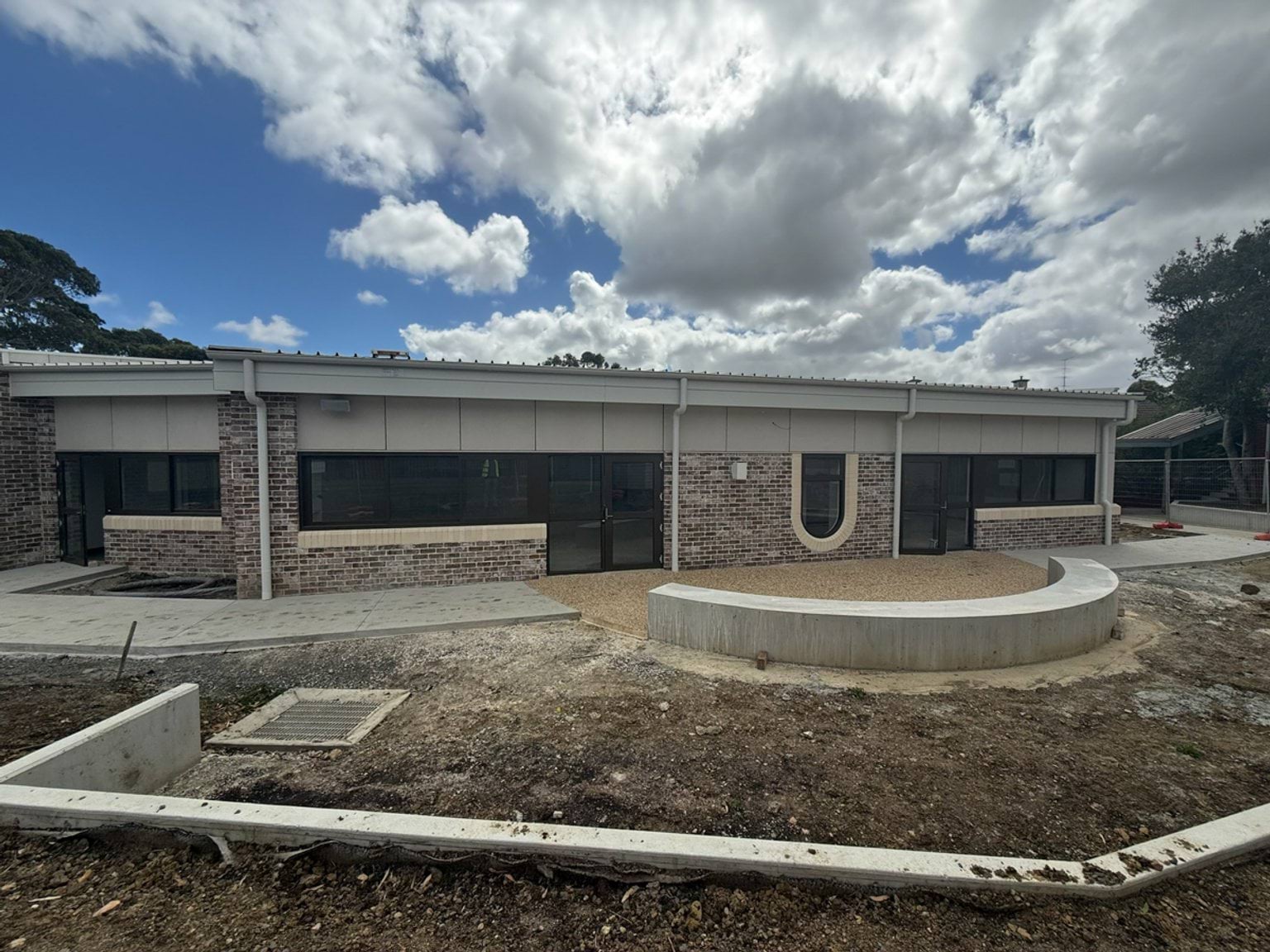 New school building with brick work, windows, and a cloudy blue sky overhead