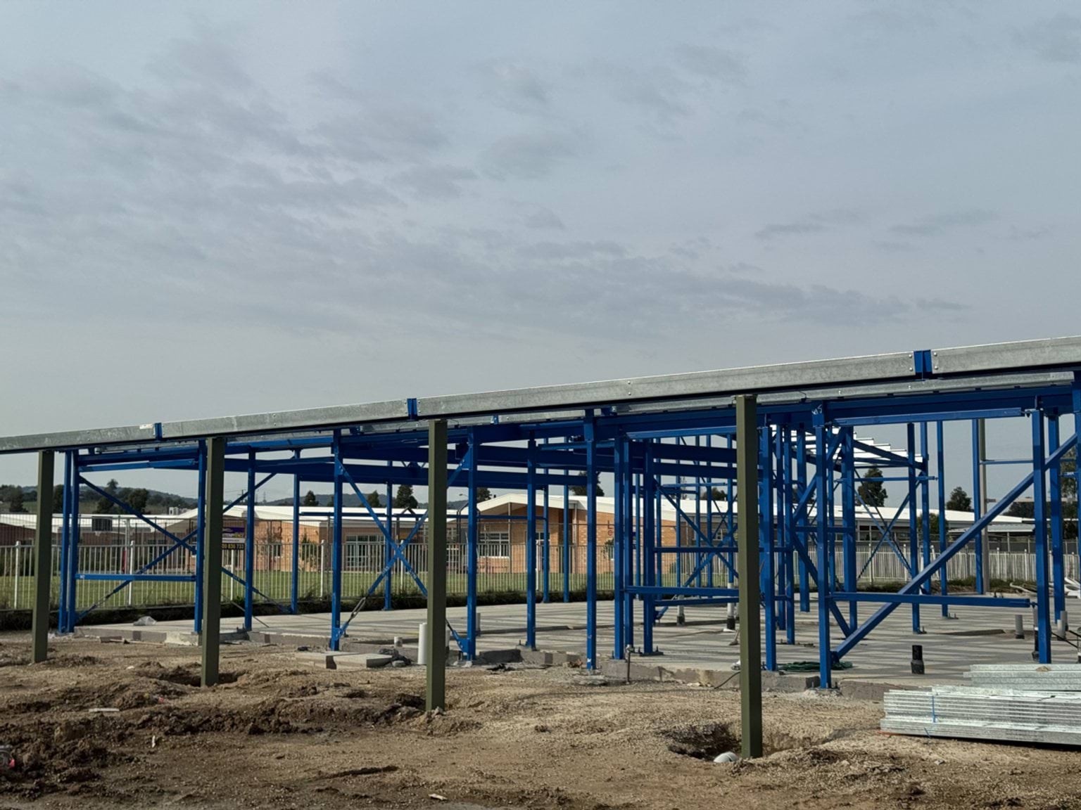 Steel structural frame of a school building with roof decking installed and concrete slab below.