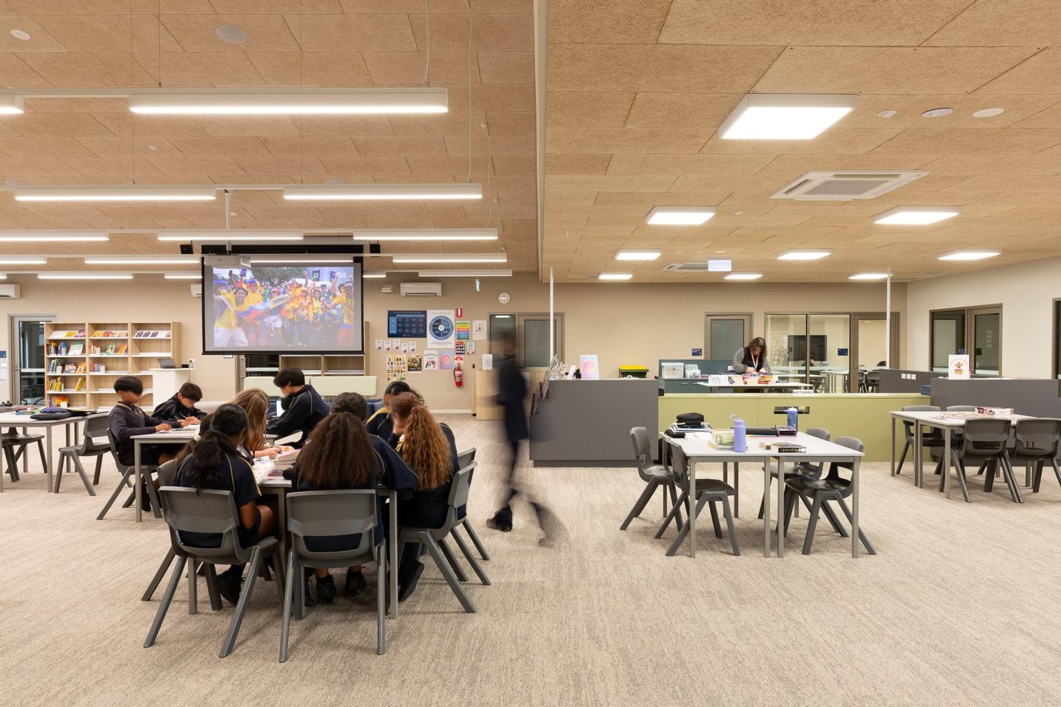 Students seated around tables in open classroom space