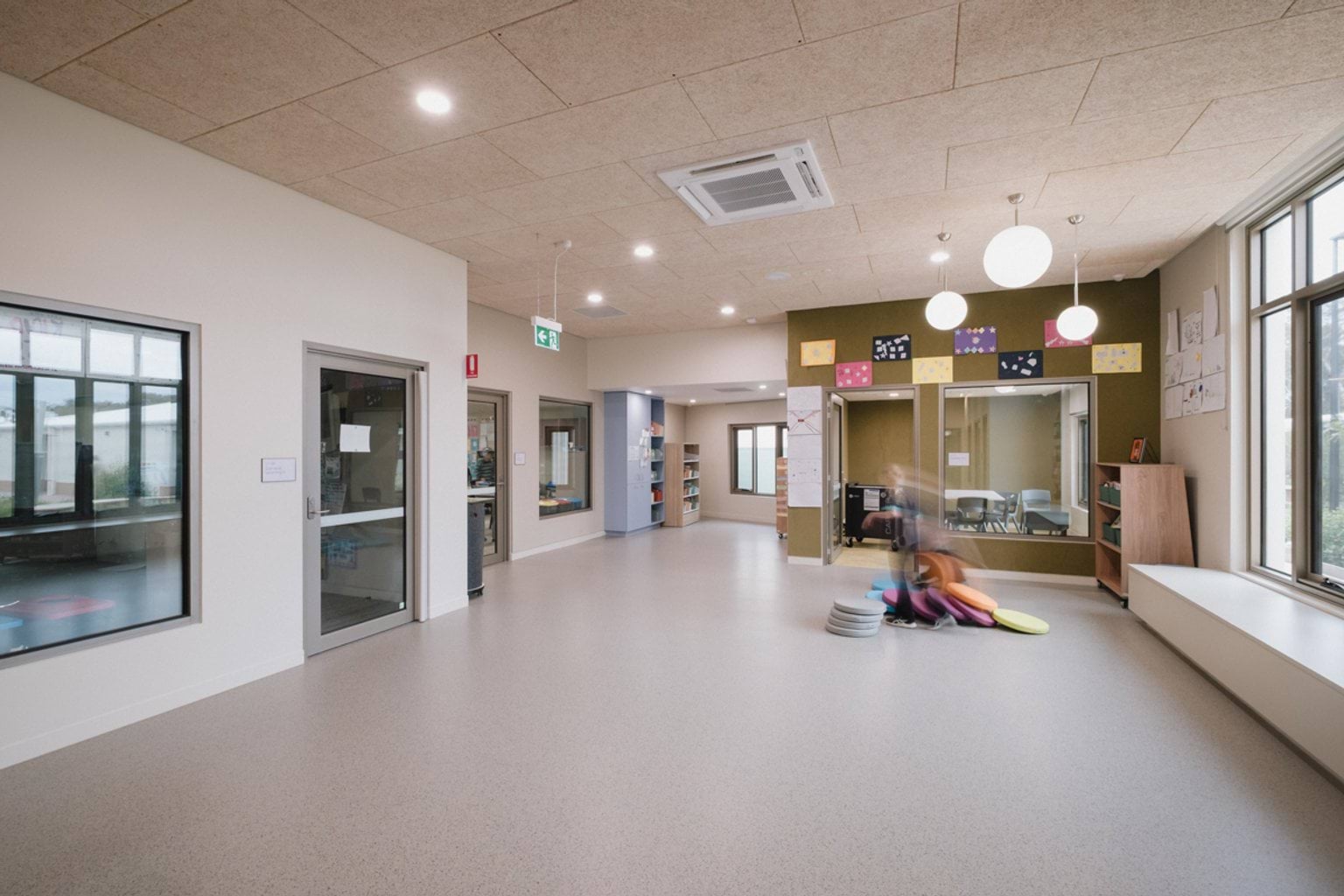 Open foyer area with white bench along window and doorways leading to classrooms and offices