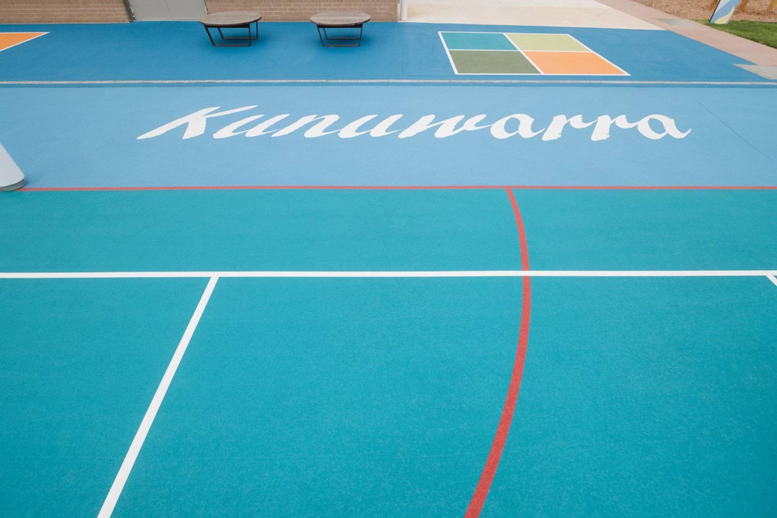 Blue outdoor court area with wording saying 'Kunuwarra'