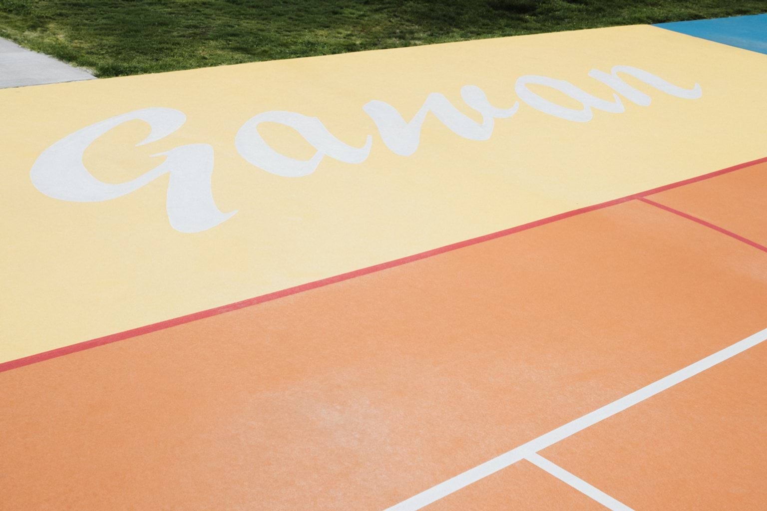 Coloured outdoor court area with court lines and letters spelling 'Gawan'