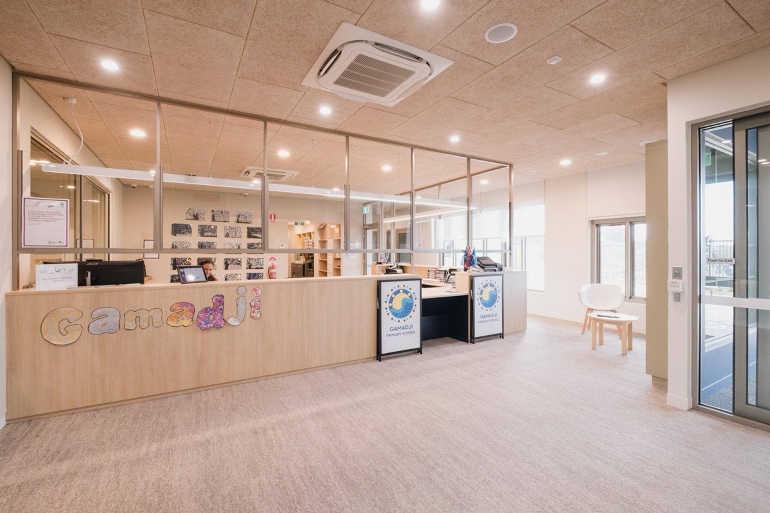 Carpeted reception area with desk, glass windows and handmade cut out letters saying 'Gamadji'