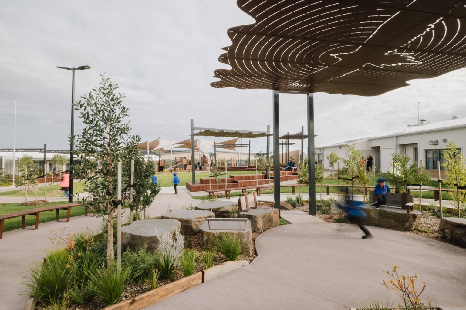 Outdoor paved area with shelters, benches and garden beds