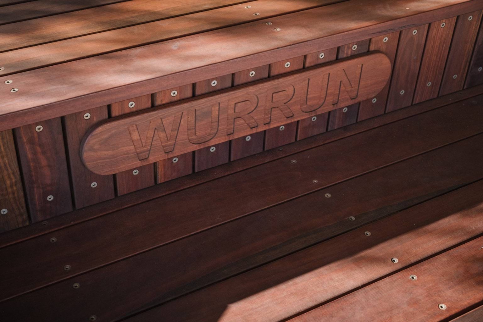 Wooden bench with engraved plate with the letters 'WURRUN'